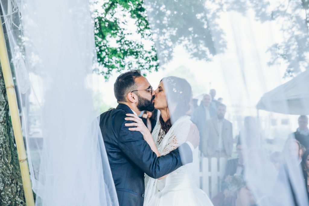 mariés s'embrassant durant la cérémonie en extérieure