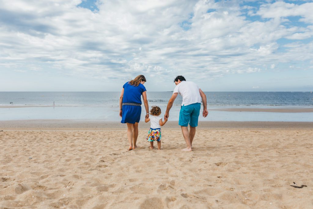 Deux parents avec leurs petites filles de dos se tenant la main en bord de mer
